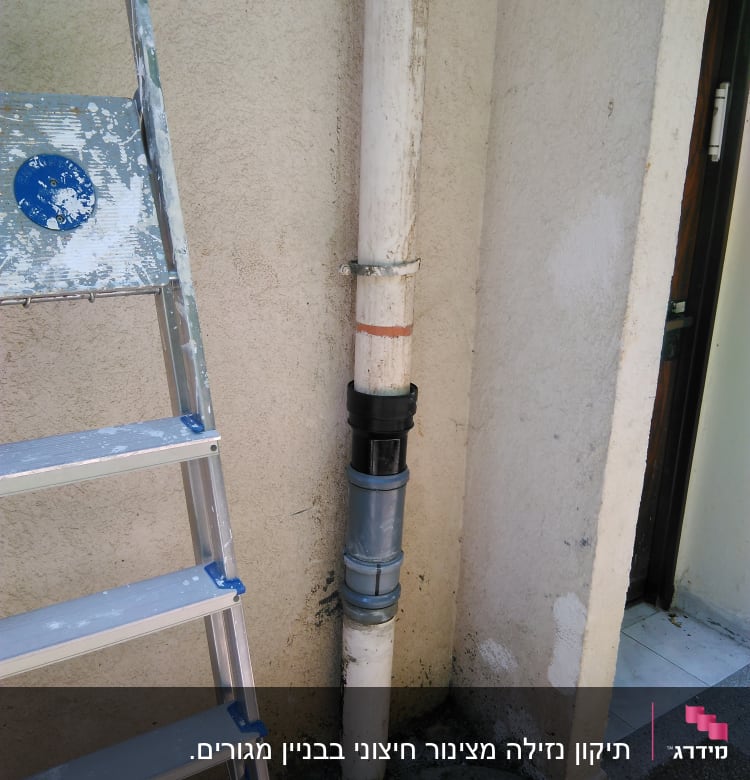 צינור מים עם חיבורי מתכת ליד סולם